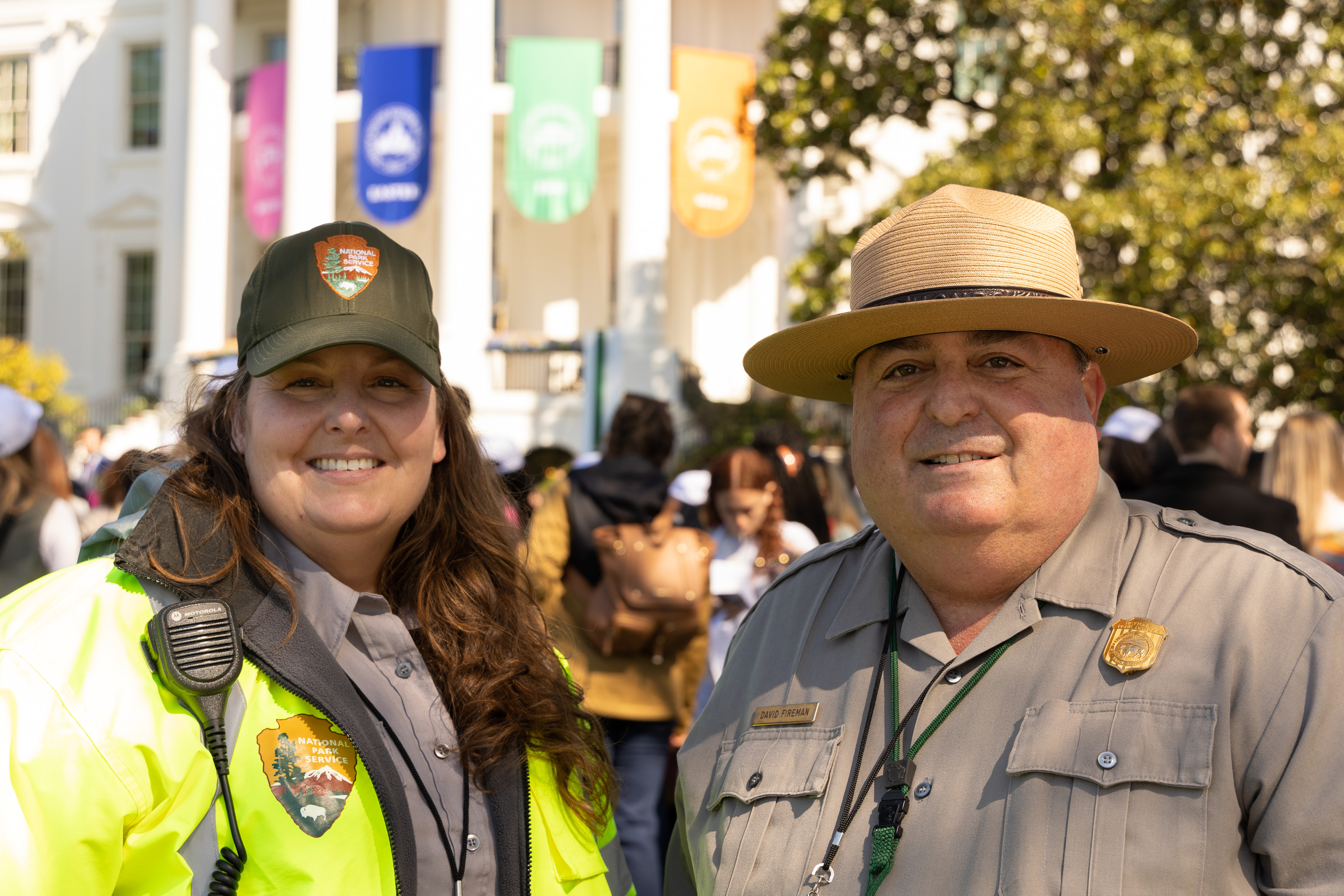 Two park rangers smile in front of the White House