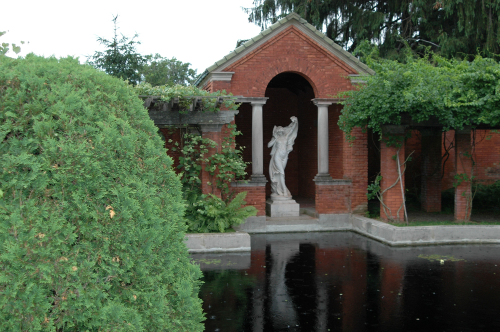 A marble statue of a woman in dance before a reflecting pool.