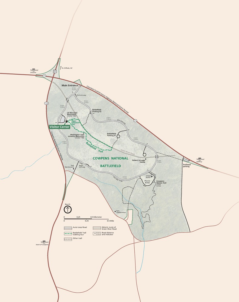 Map of Cowpens National Battlefield in South Carolina. The park is shaded in light teal with the surrounding area in tan. Highways are represented with red lines, park roads with white lines, and park trails with green or black dashed lines.