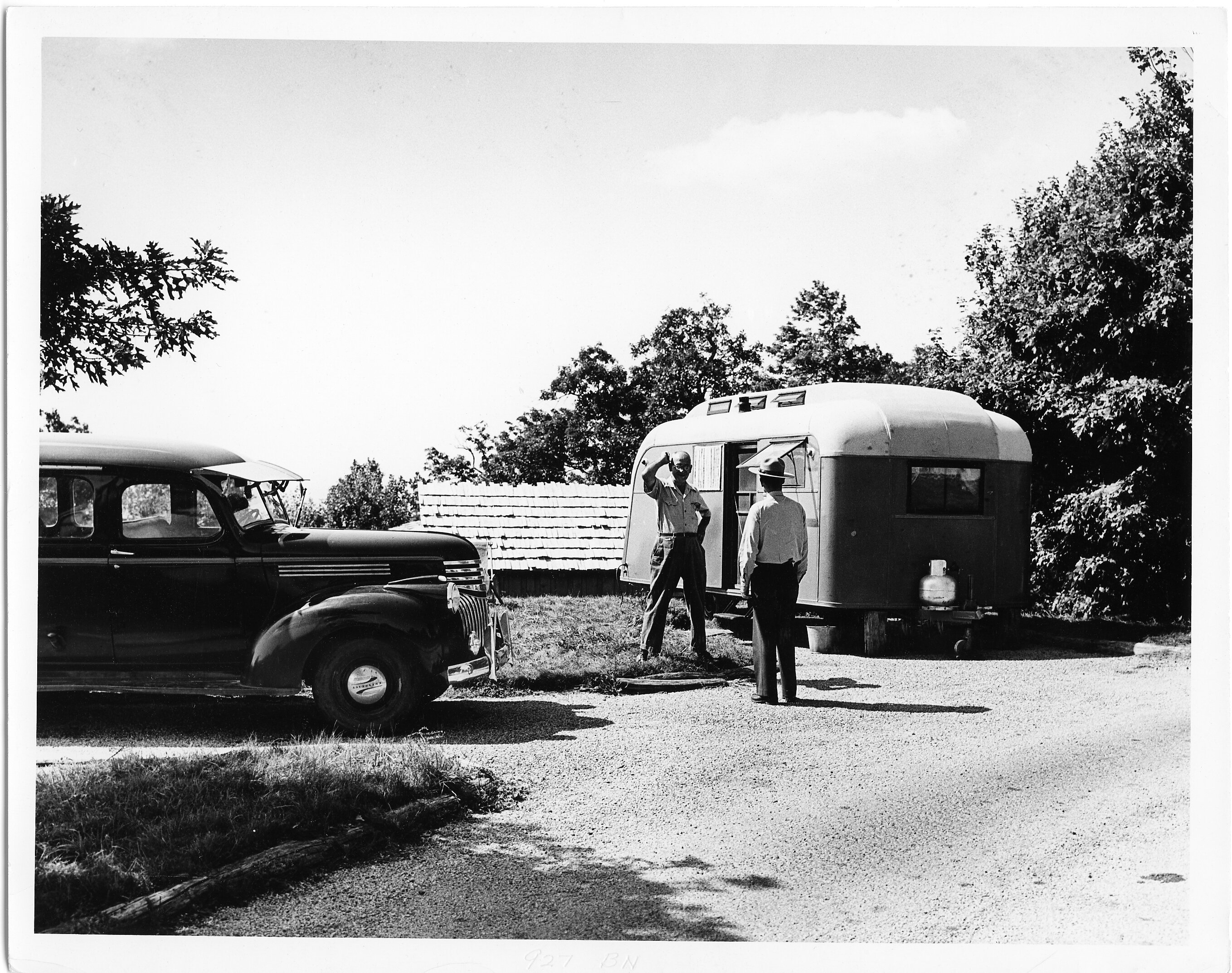 Two visitors stand by a trailer and a car