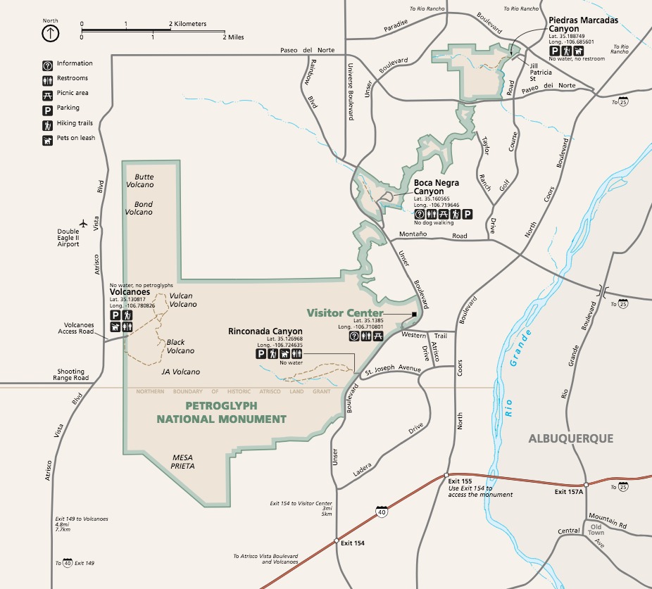 Map of Petroglyph National Monument in New Mexico. The park grounds, pale yellow with sage green borders against the white surrounding lands, are roughly triangular with a stovepipe shape that juts straight north at the northwest corner and an appendage that runs northeast like a ball of yarn.