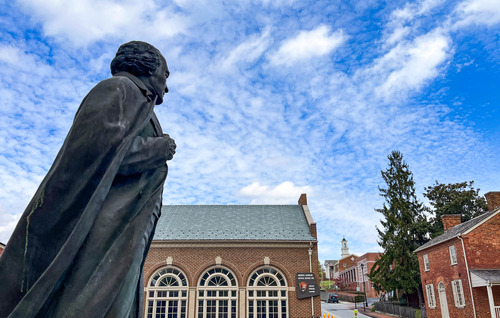 Statue of Andrew Johnson in across the street from a brick building with prominent arched windows and a historic brick home