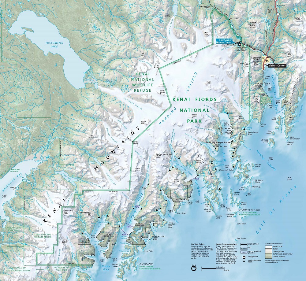 Map of Kenai Fjords National Park, which stretches along the southwest coast of the Kenai Peninsula in Alaska. The land is shown green at lower elevations and is frosted with white at higher altitudes, and the water has shades of blue, representing differences in water depth. A zigzagging green outline marks the border between the Kenai National Wildlife Refuge to the west and Kenai Fjords National Park to the east.