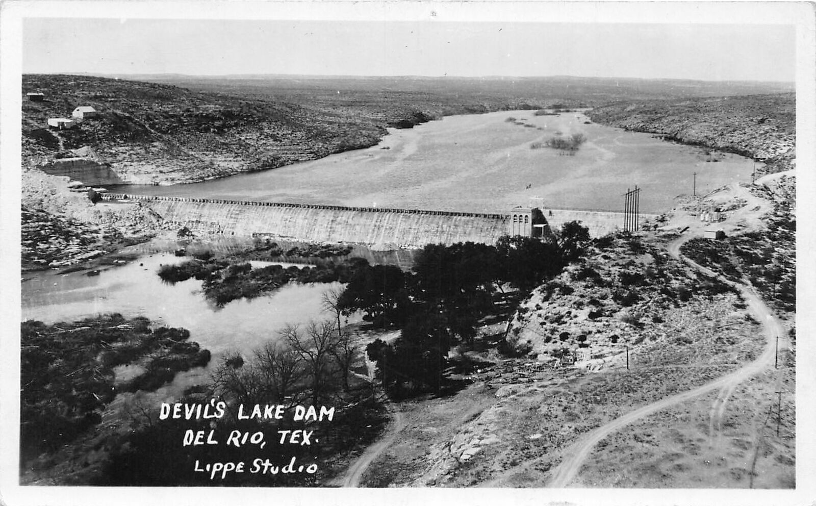 Black and white aerial view of full span of completed Devils Lake Dam