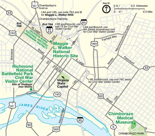 Map of Maggie L. Walker National Historic Site in Virginia. The site is labeled with green text against the pale-yellow grid of white and gray city streets. Three other sites are labeled in green text, two are shaded in green, one area is darker yellow, and other sites are labeled with black text. The blue James River runs along the bottom of the map, starting from the west side and bending south.