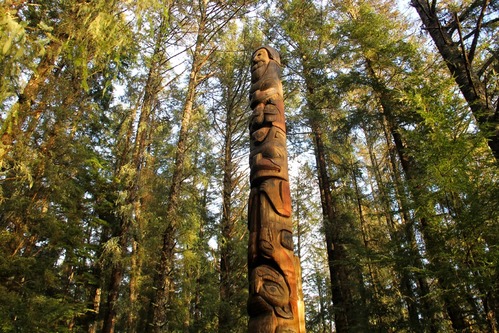 Faded totem pole topped by a figure representing a white man with curly hair and beard.