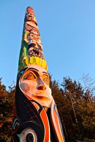 Totem pole painted with a variety of vivid colors – red, yellow, green, blue, black, and turquoise.
