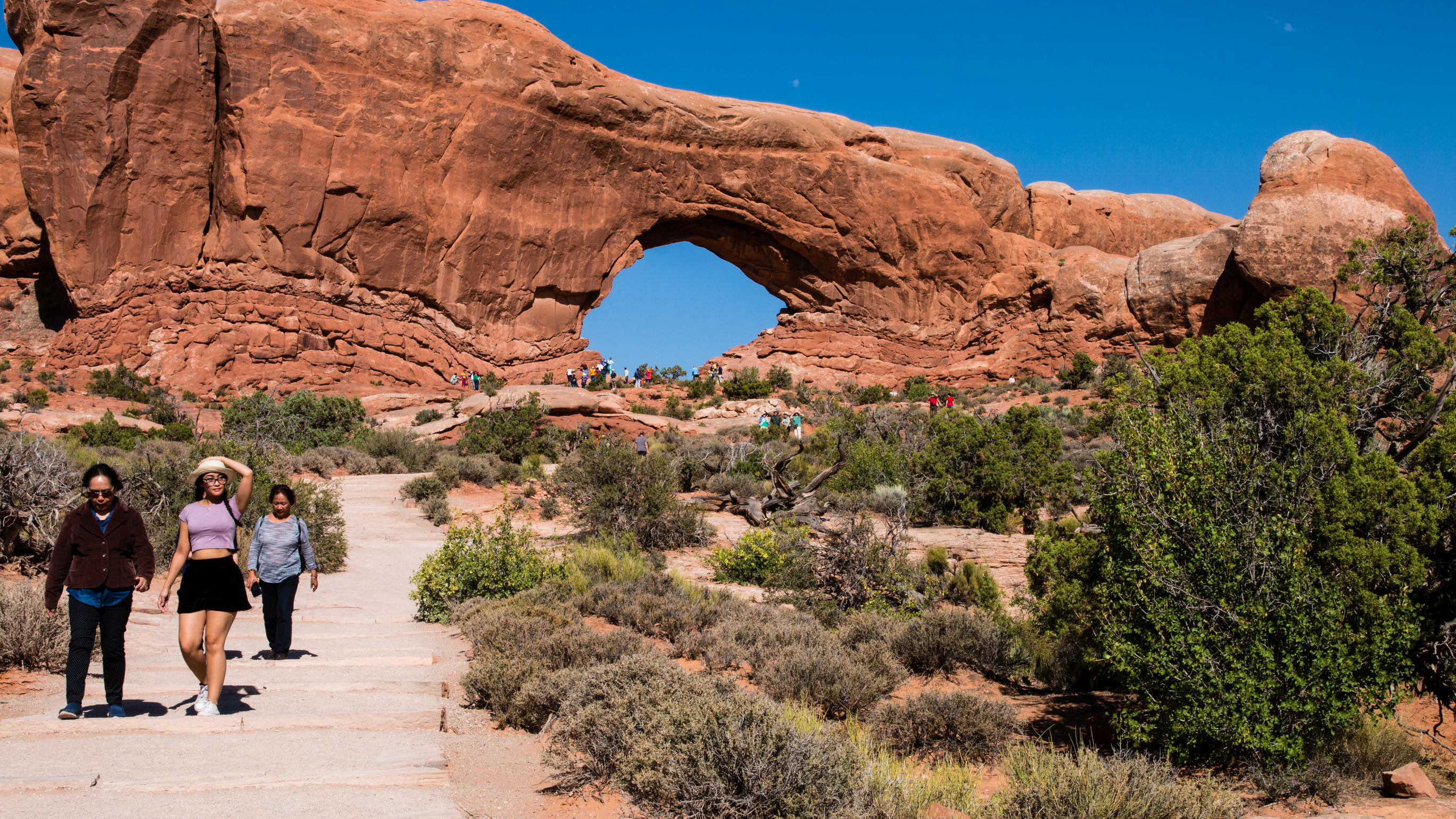 Visitors walk along a paved pathway at Arches National Park. Photo by M. Reed, NPS.