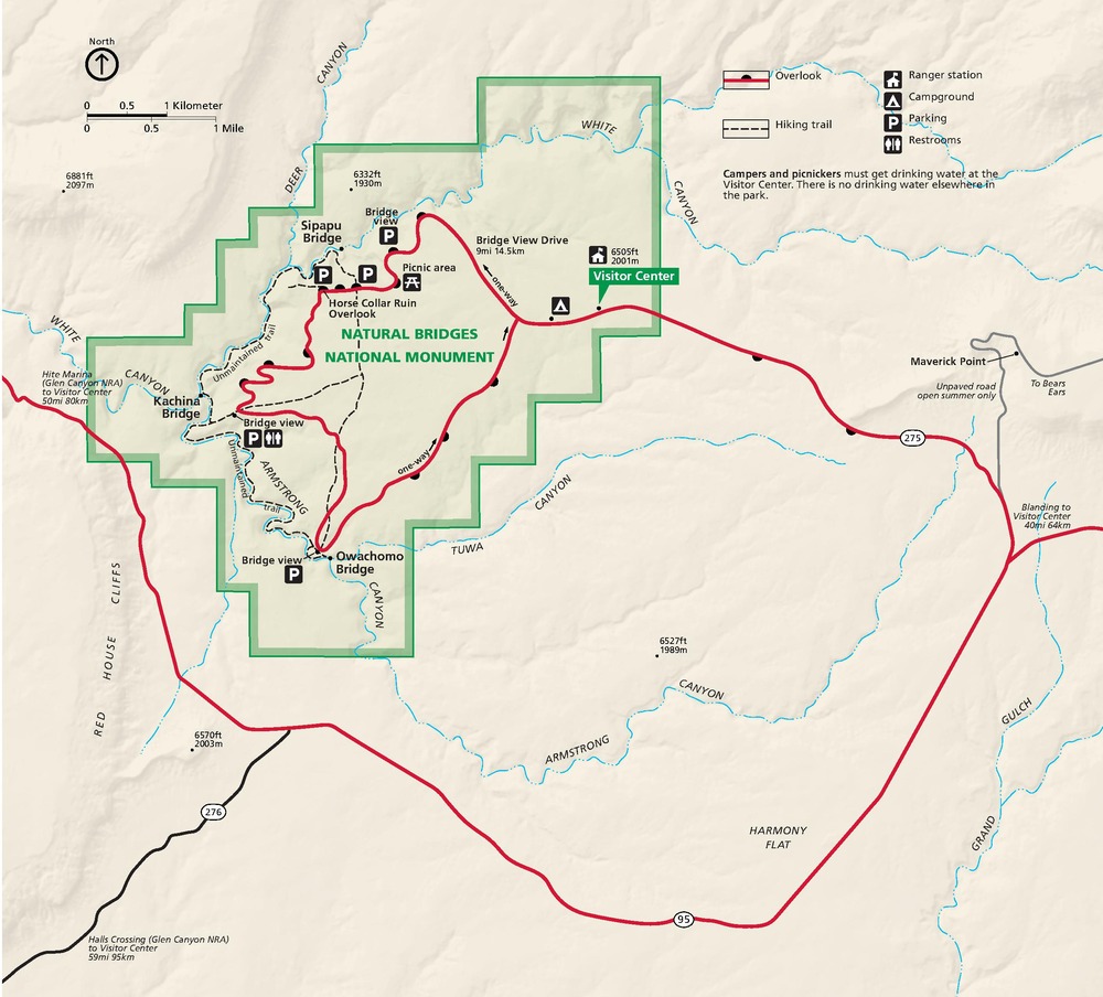 Map of Natural Bridges National Monument in Utah. The park is shaded green and has stepped boundaries. A park road, shown as a red line, creates a circuit through the monument. Surrounding terrain is shown in tan.