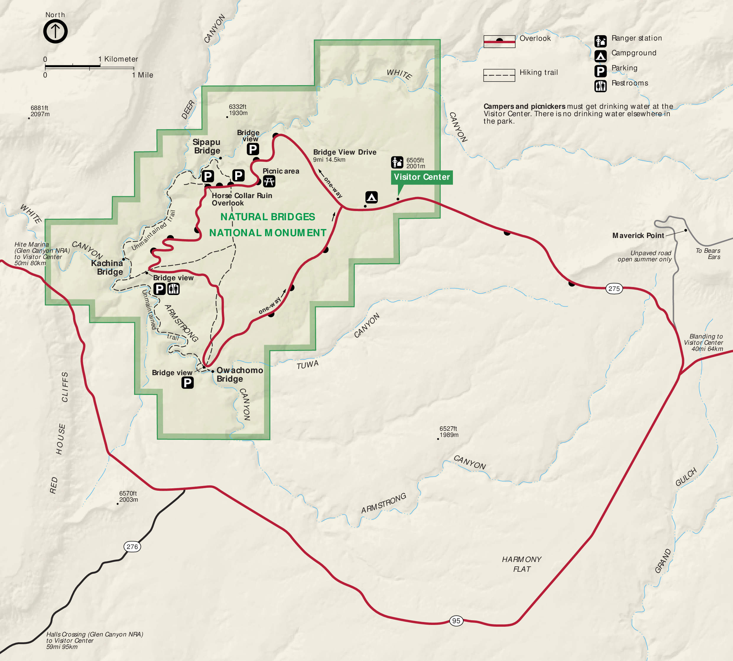 Map of Natural Bridges National Monument in Utah. The park is shaded green and has stepped boundaries. A park road, shown as a red line, creates a circuit through the monument. Surrounding terrain is shown in tan.