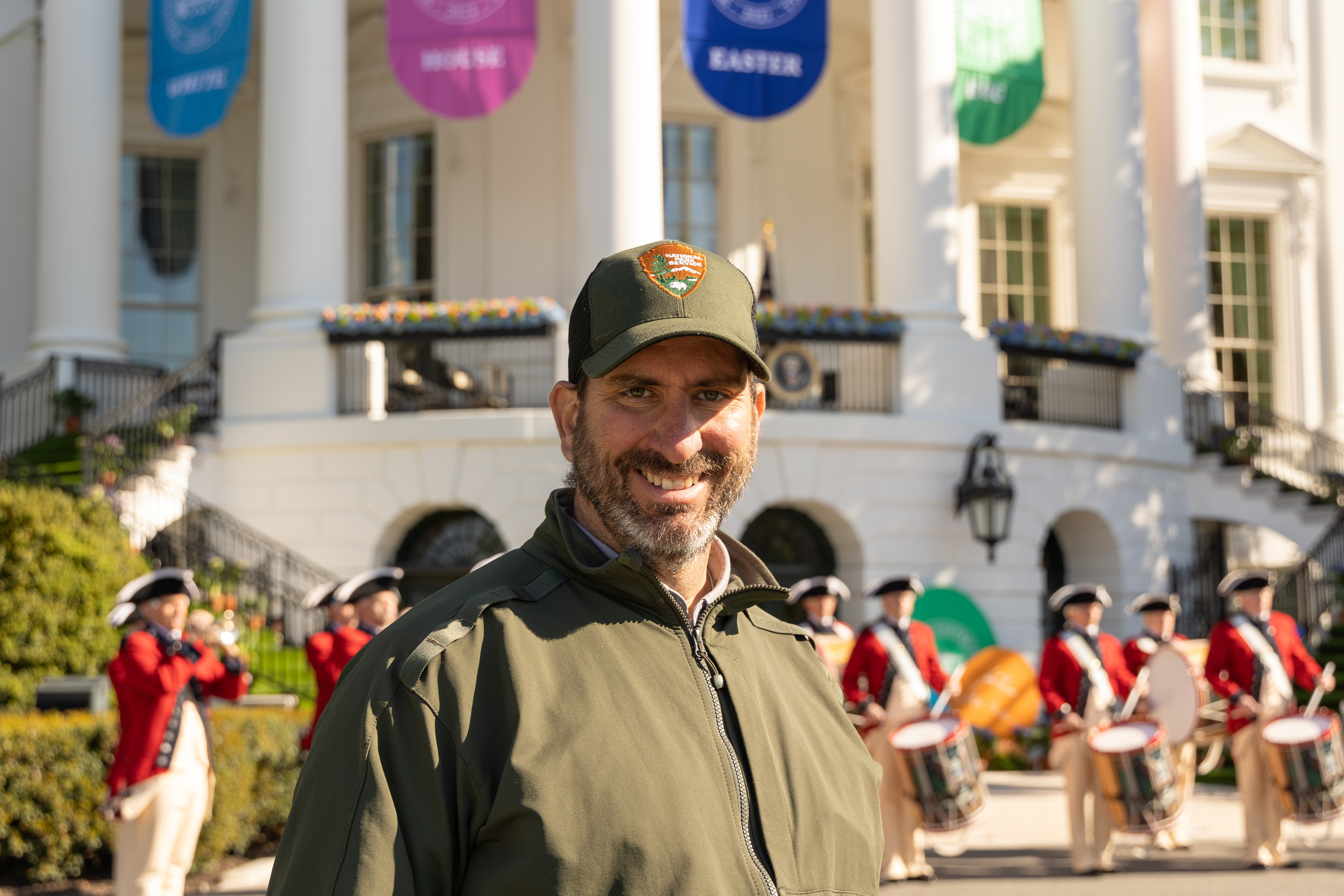 A park ranger smiles in front of the White House