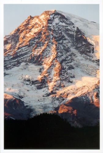 The sun dappled, craggy face of Mount Rainier seen at the end of summer.