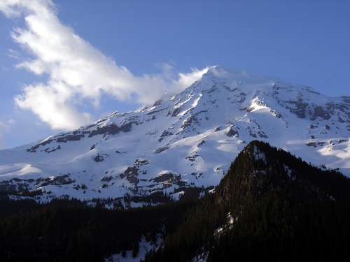 Patches of light gleam on a snow-covered mountain peak against a blue sky. 