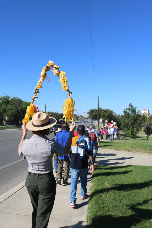 Park Ranger walks behind a line of people to Mission Marquee Plaza. 