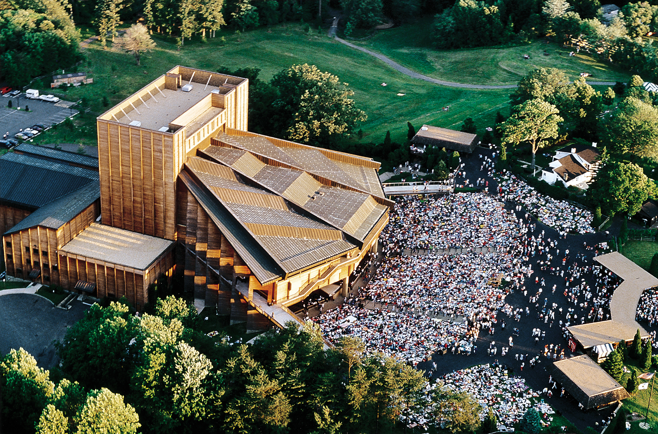 An aerial view of the Filene Center with several hundreds of people surrounding it. 
