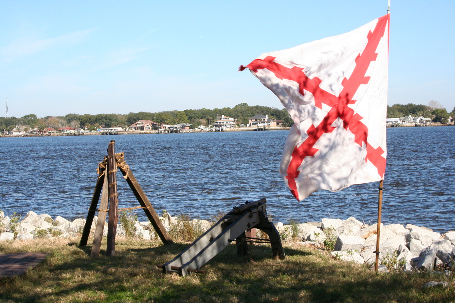 flag and cannon next to river.