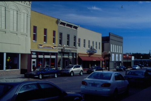 Image of a streetscape with cars and shops.