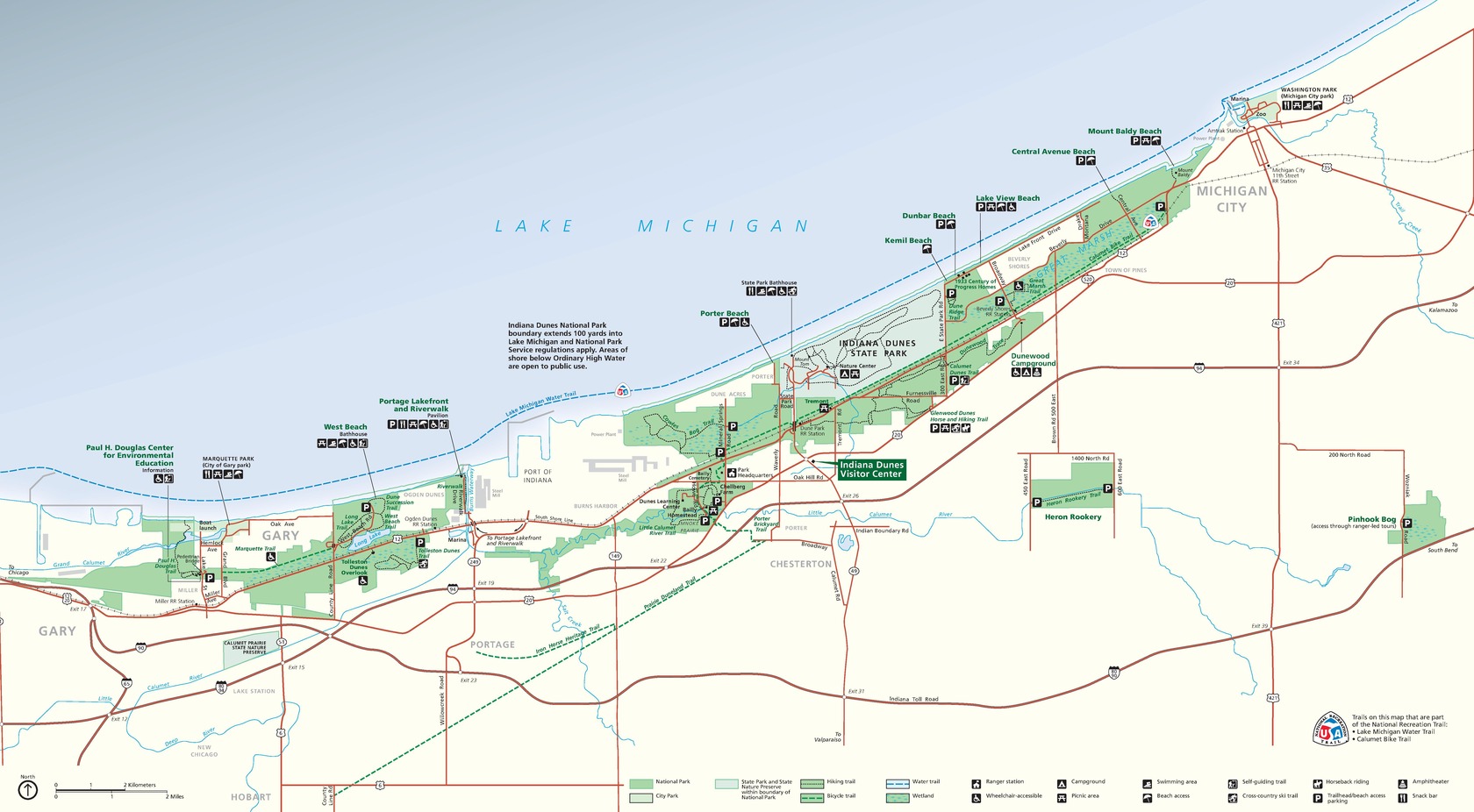 Map of Indiana Dunes National Park in Indiana. Park areas are shown in grass or frosty green on cream-white land against the blue water of Lake Michigan. A network of roads is shown in red.