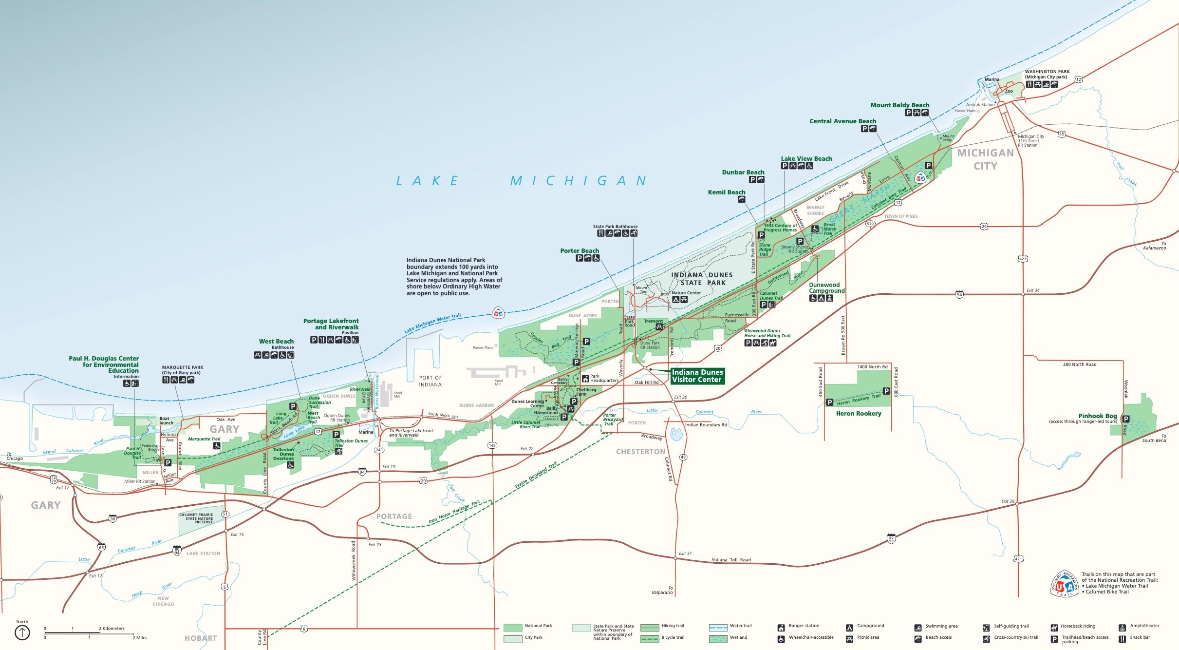 Map of Indiana Dunes National Park in Indiana. Park areas are shown in grass or frosty green on cream-white land against the blue water of Lake Michigan. A network of roads is shown in red.