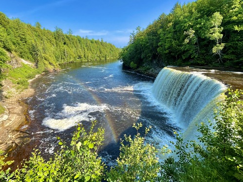 A rainbow next to a wide waterfall