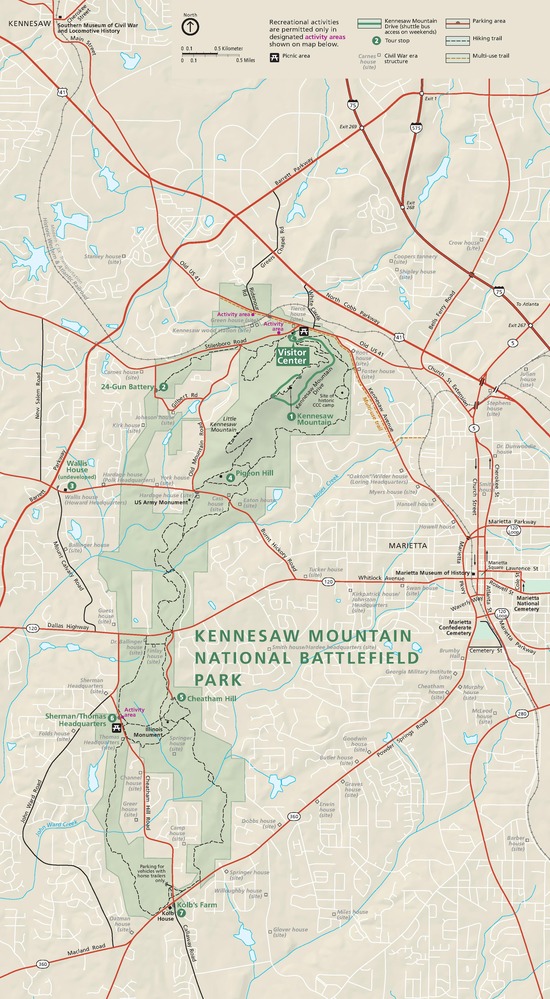 Map of Kennesaw Mountain National Battlefield Park in Georgia. The map is tan with the tall, narrow park is highlighted in green. Major highways are represented by red lines and park trails by dashed black lines.