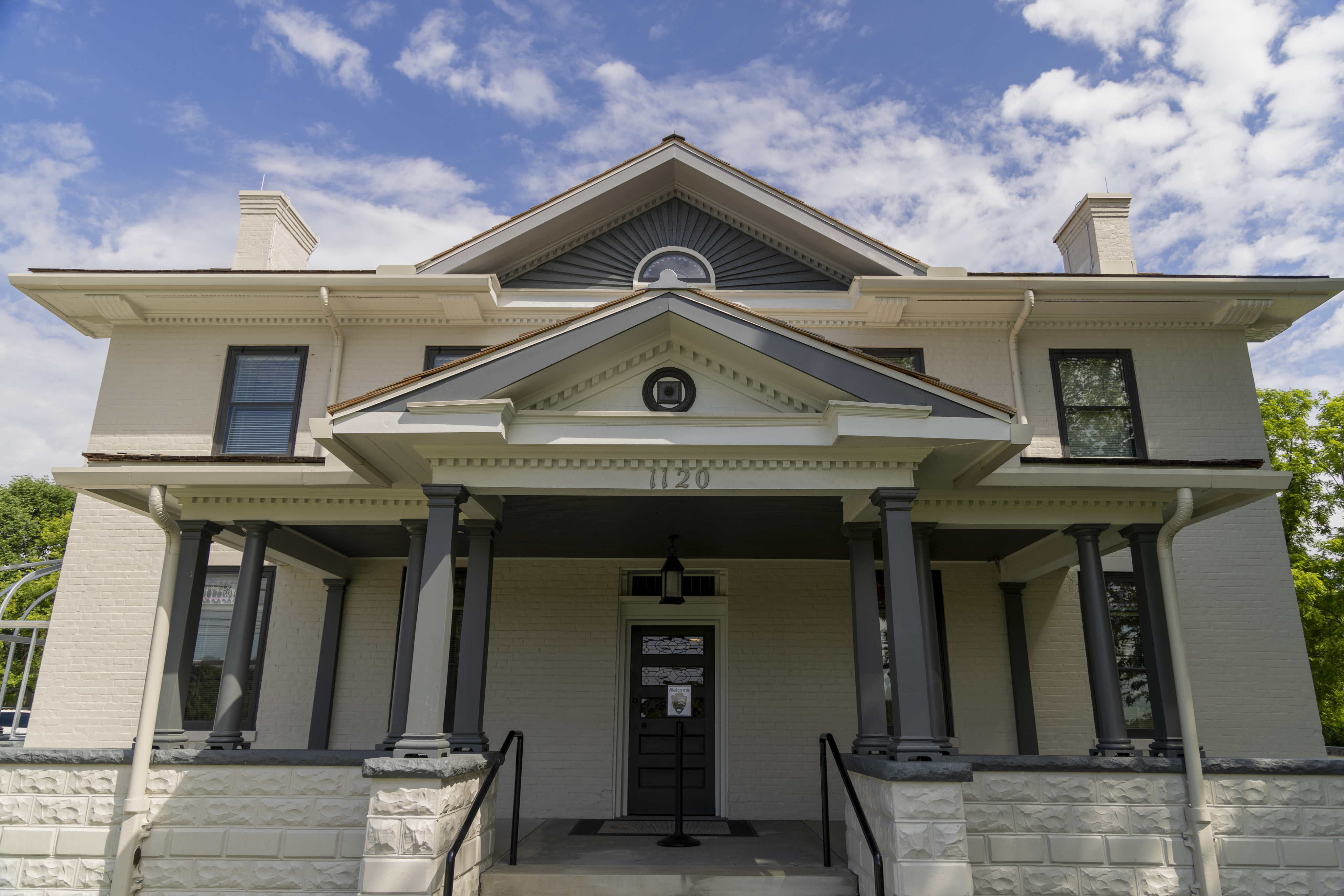 A light-colored house with a peaked roof on the first and second floors of the home.