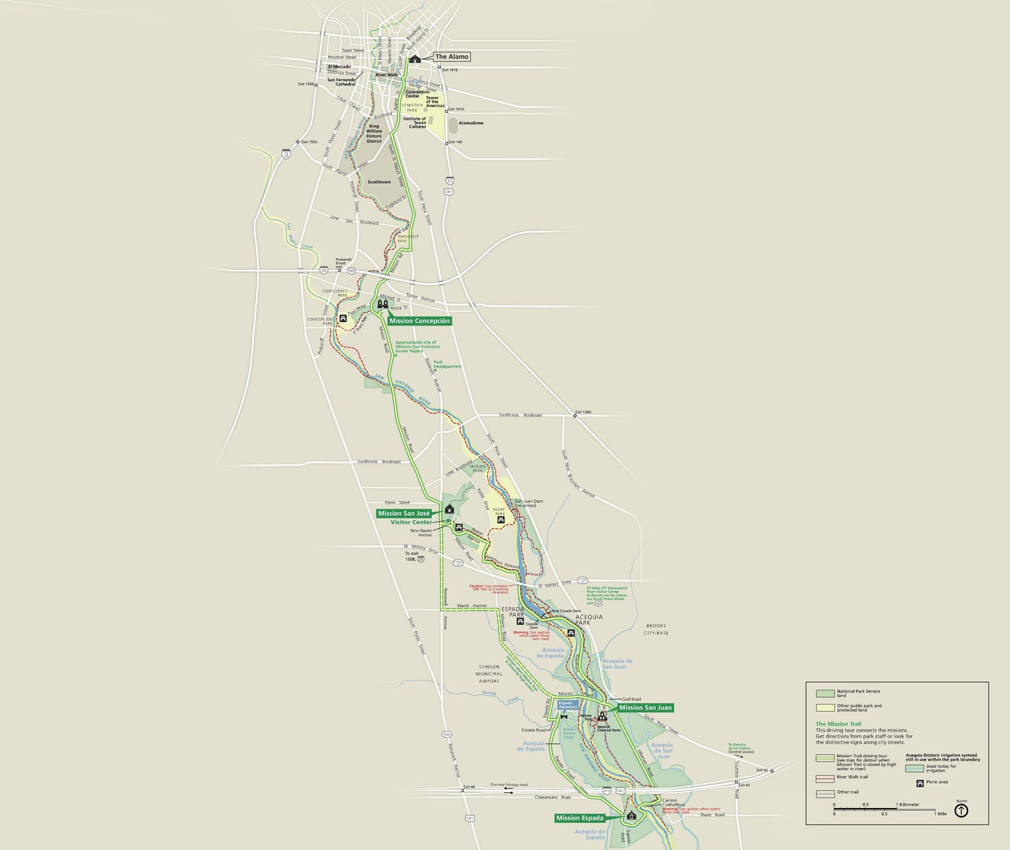Map of San Antonio Missions National Historical Park in Texas. The San Antonio River, shown in blue, and the Mission Trail connect four missions labeled with green callout boxes and green park areas. These and other sites make a loose, almost vertical line down the map. Streets are shown in white against a tan background.
