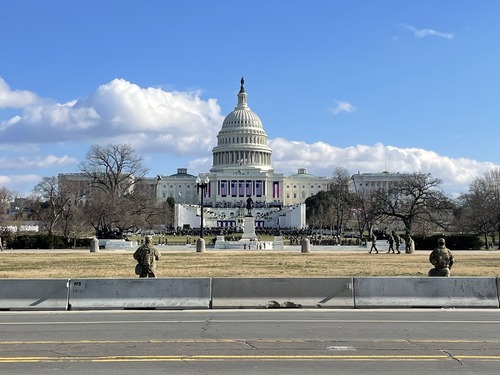 Military and police watching the U.S. Capitol building, which is decorated with U.S. flags and red, white, and blue banners