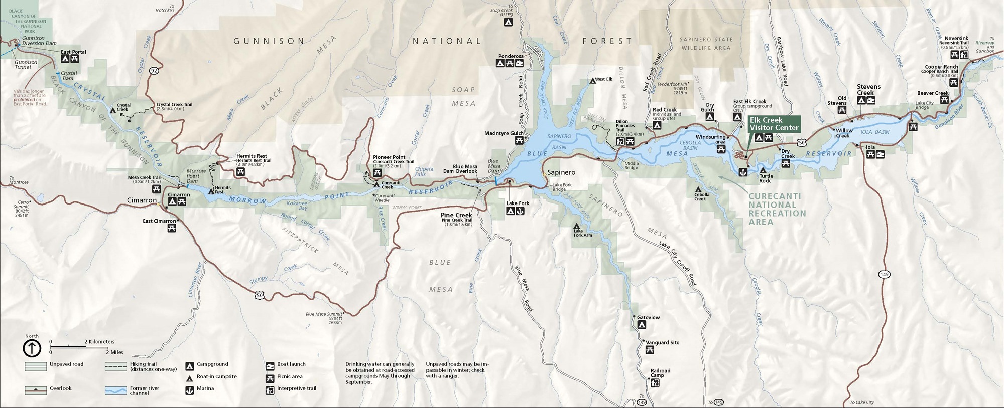 Map of Curecanti National Recreation Area in Colorado. Park areas, shown in green, stretches across the north and south banks of the Gunnison River, represented as a blue waterway of varying widths from the top left corner to the top right edge. Surrounding terrain is shaded in beige.