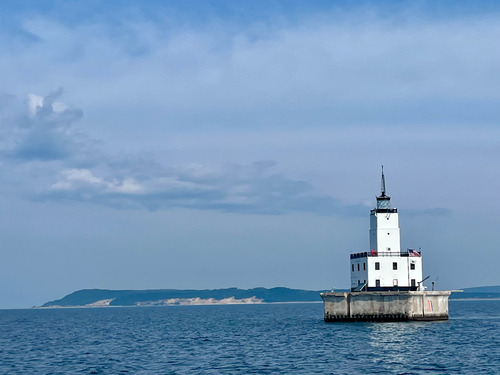 White lighthouse with red roofs on a concrete island in a large lake