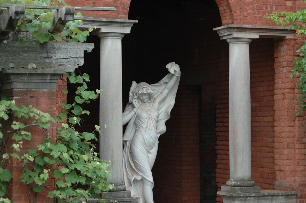 A marble statue of a female figure in dance, surrounded by a brick pavilion with stone columns.