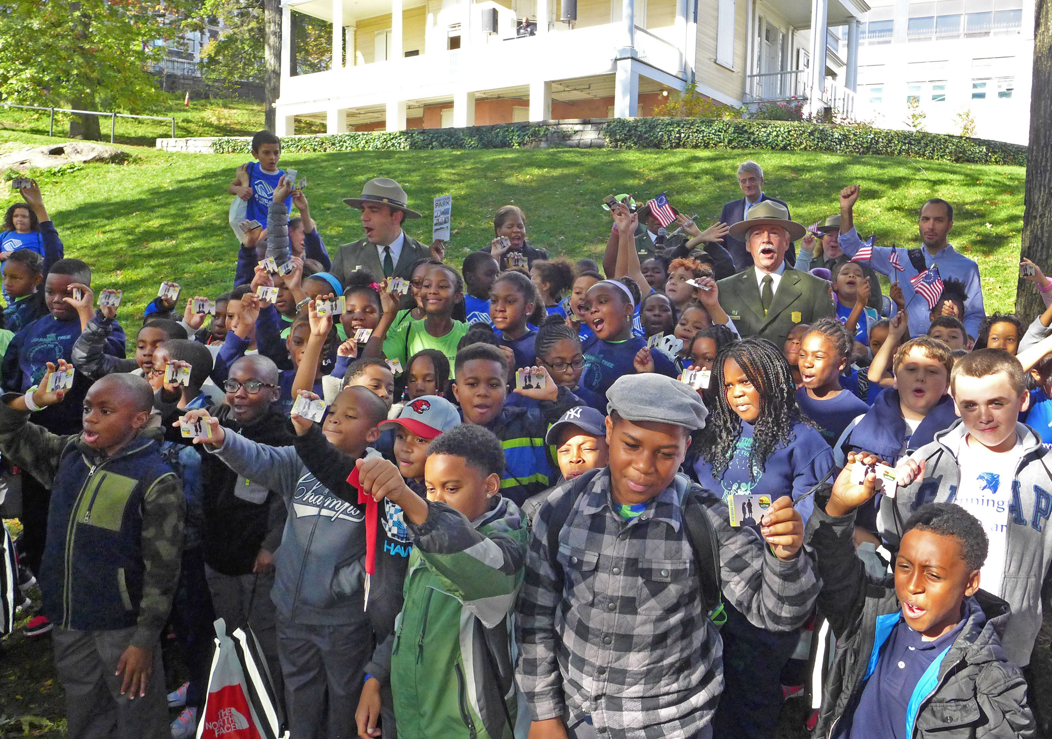 Fourth graders at an event in Hamilton Grange National Memorial hold up their Every Kid in a Park passes.