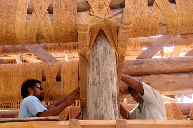 Samoan workers fasten beam structures of the fale.