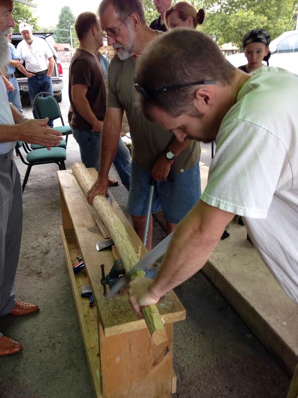 several people working on wood to create a bow