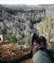 hiker sitting on edge of cliff observing the gorge