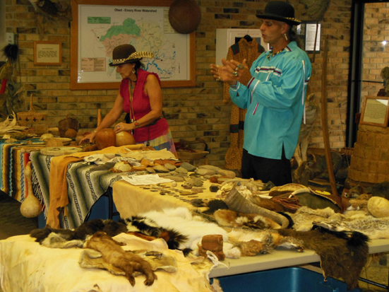 Native American woman and man demonstrating way of life with animal hides