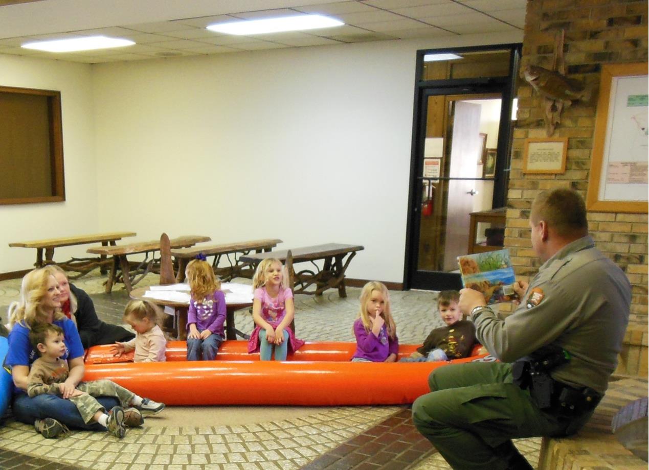 Park ranger reading to young kids sitting in kayak
