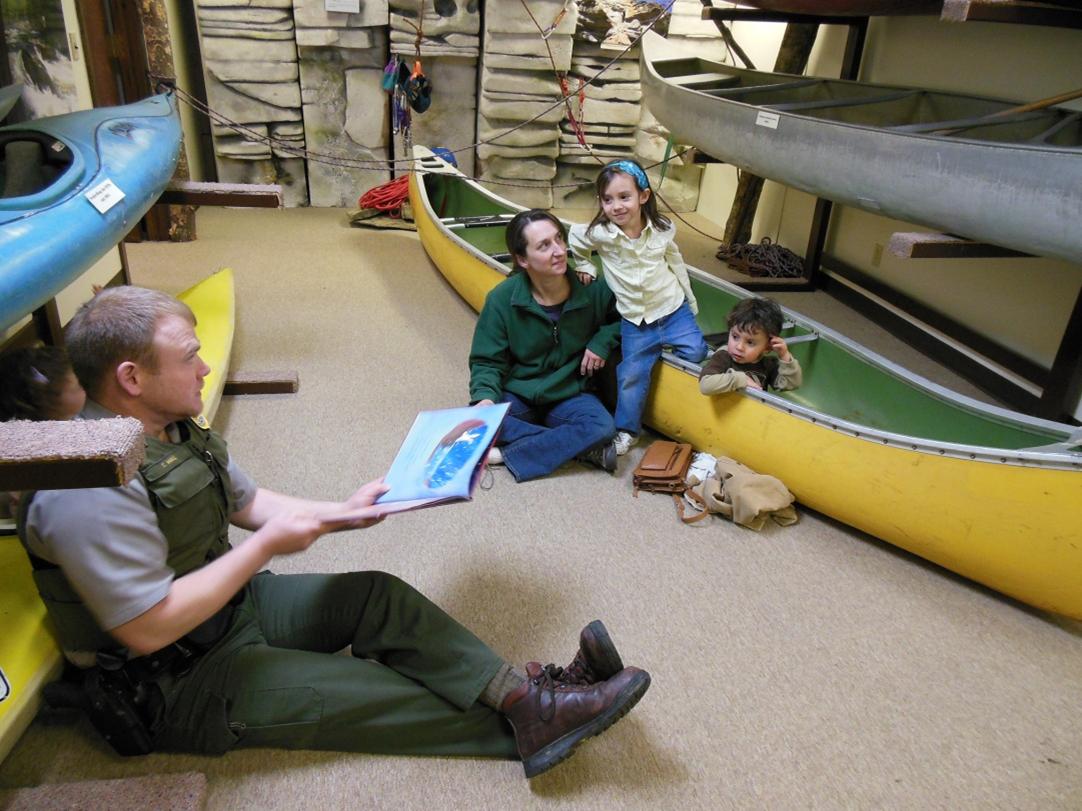 Park ranger reading story from book for little toddler