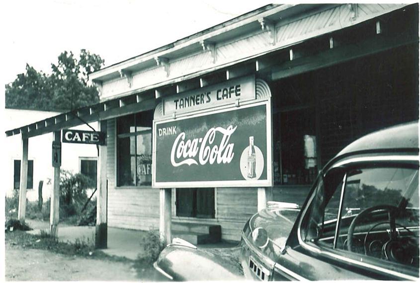 old Coca-Cola sign in front of store with old car