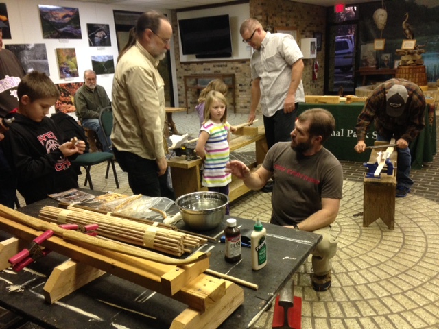 several people working on a primitive bow during a workshop