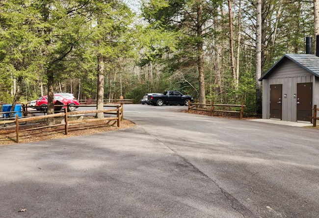 Parking lot that shows parking and a vault toilet.