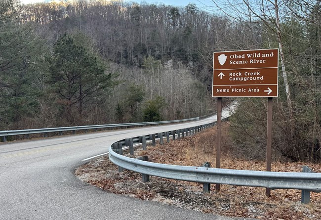 Brown national park directional sign pointing two different directions on the side of the highway.