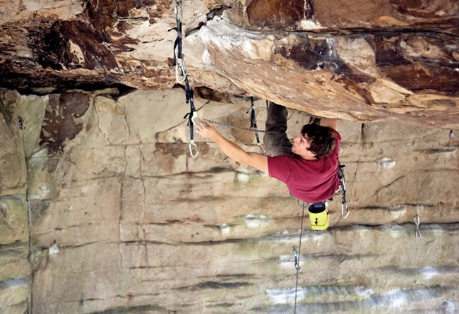 A man rock climbing hanging clipping in.
