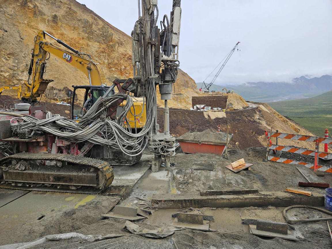 Drill rig A drill rig positioned atop a cementous abutment drilling into the rock