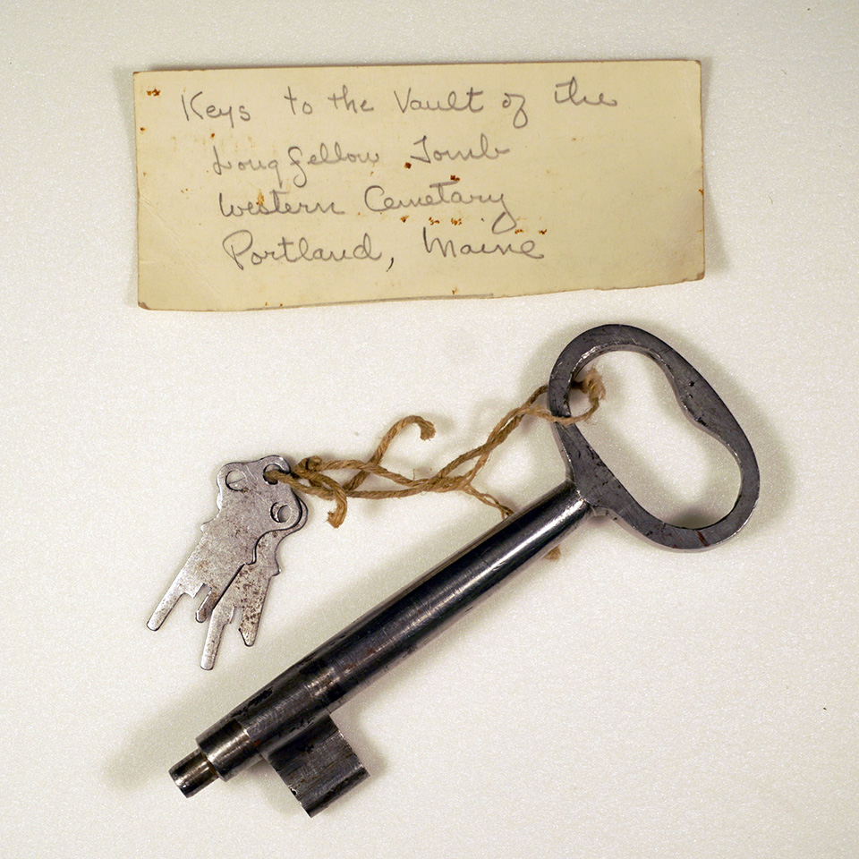 A large metal key to a cemetery tomb along with two smaller keys and a handwritten note.