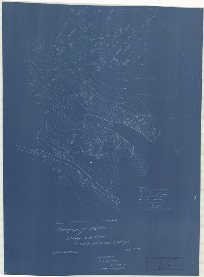 White lines on blue paper with topographical lines and buildings on the hill.