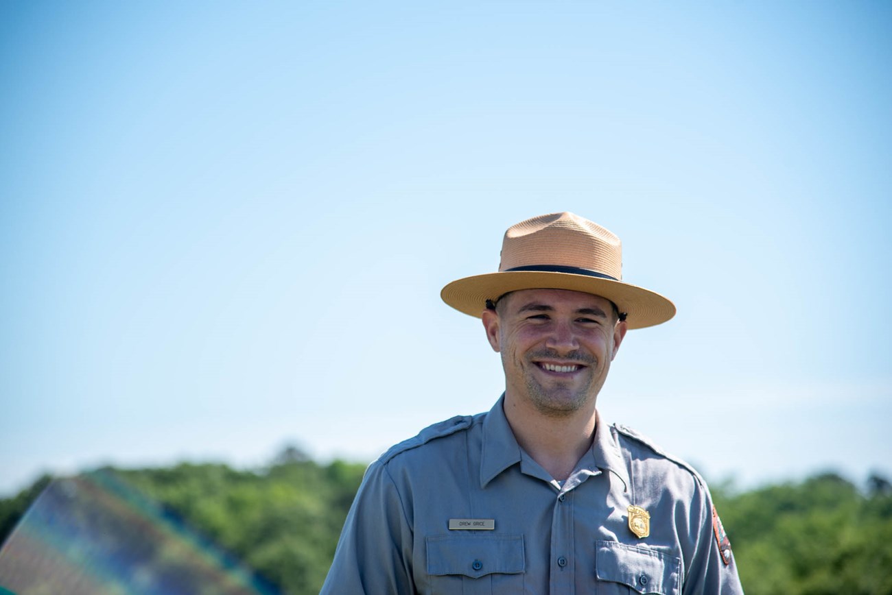 Ranger Drew A park ranger smiling against a blue sky.