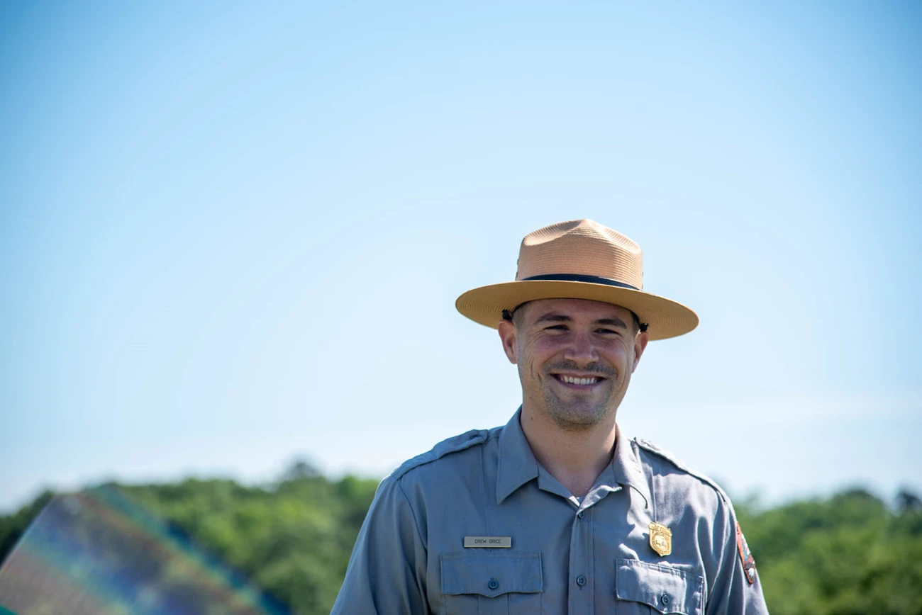 Ranger Drew A park ranger smiling against a blue sky.