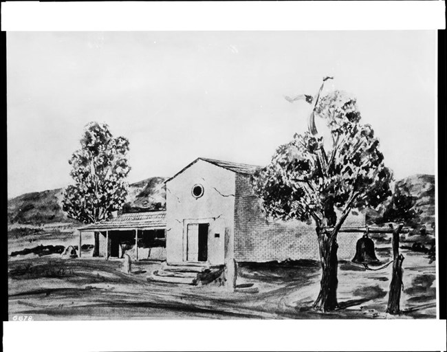 lt= A small, modest adobe church in an open setting.