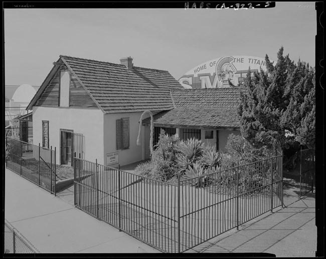 lt= A small historic home with a slanted shingled roof.